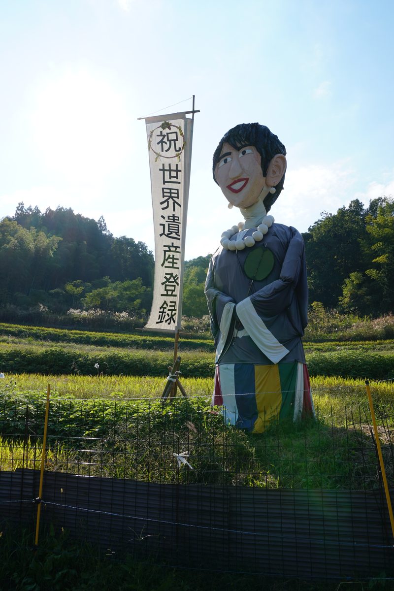 「祝 世界遺産登録」ののぼりを持つ案山子